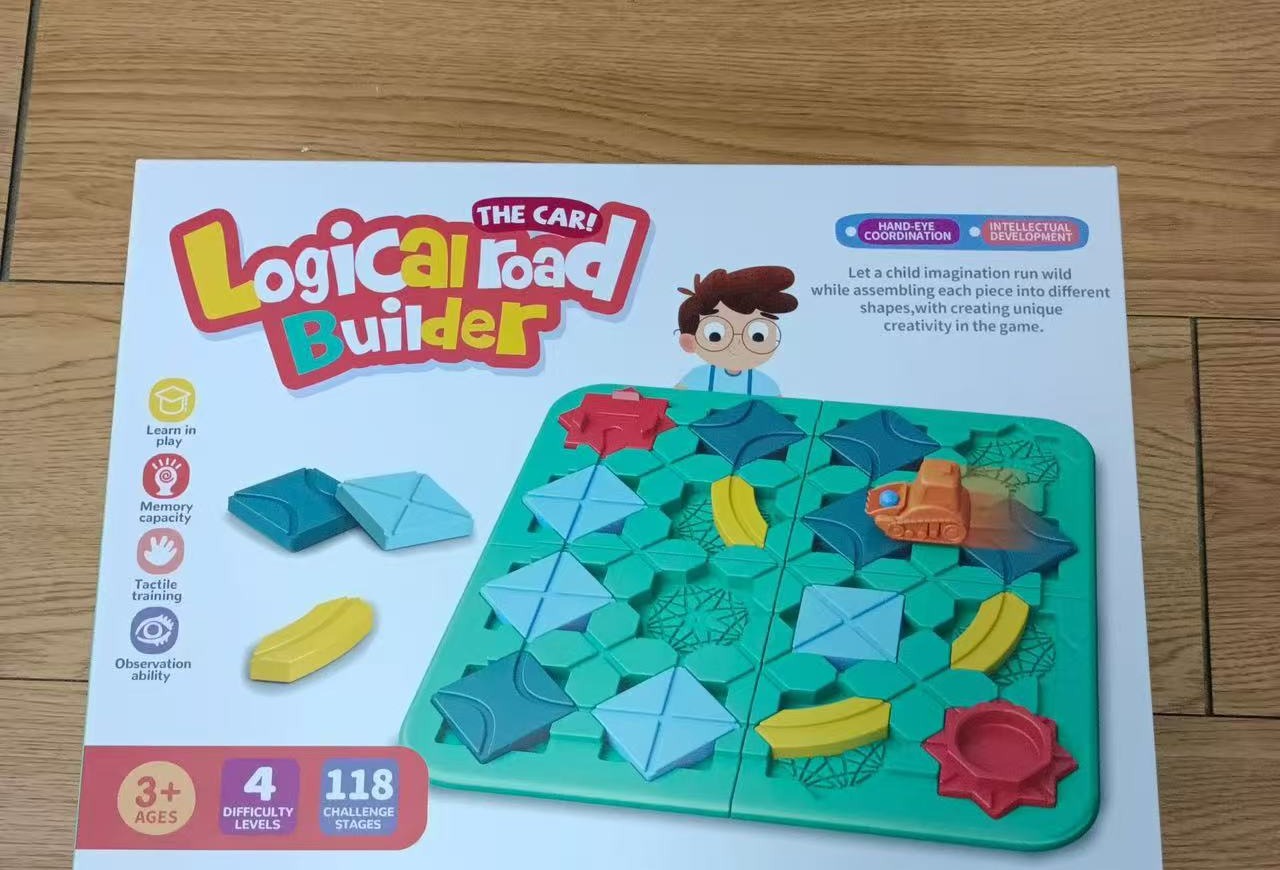 Real product photo of Logical Road Builder STEM puzzle game retail box — actual unboxed packaging showing Hand-Eye Coordination and Intellectual Development features, 4 difficulty levels, 118 challenge stages, recommended ages 3+